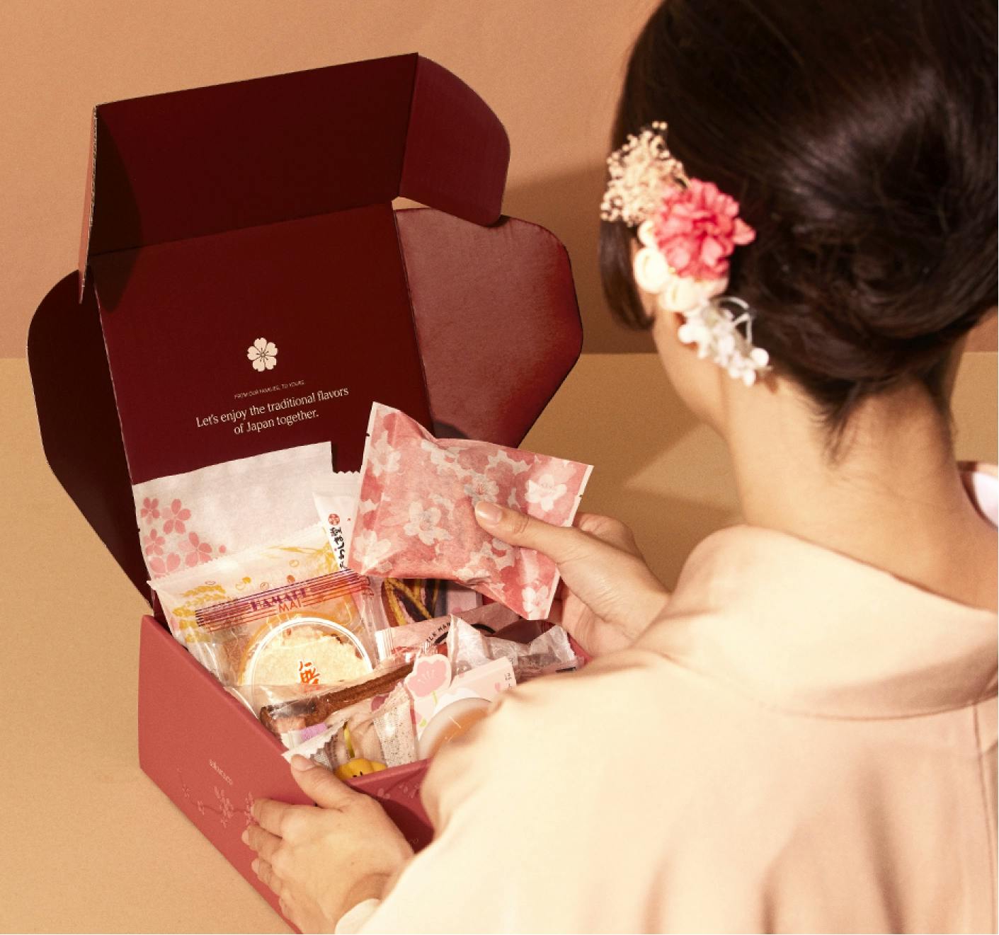 A woman in a kimono looks through a Sakuraco box.