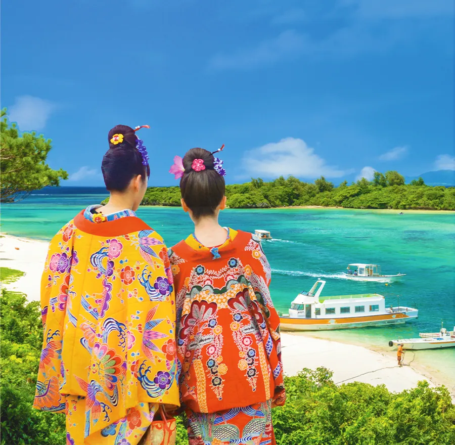 Two women dressed in traditional Okinawa bingata kimonos overlook the tropical Okinawa scenery.