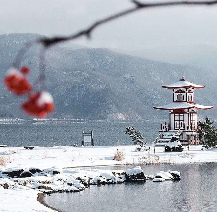 A view of Lake Toya and a pagoda located at a park with a snowy landscape.