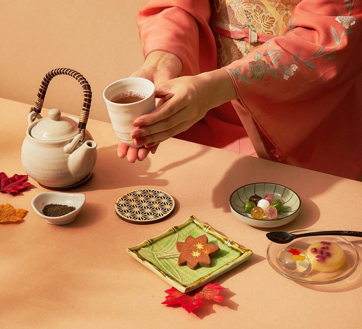 A woman sits in a kimono with tea and traditional Japanese snacks