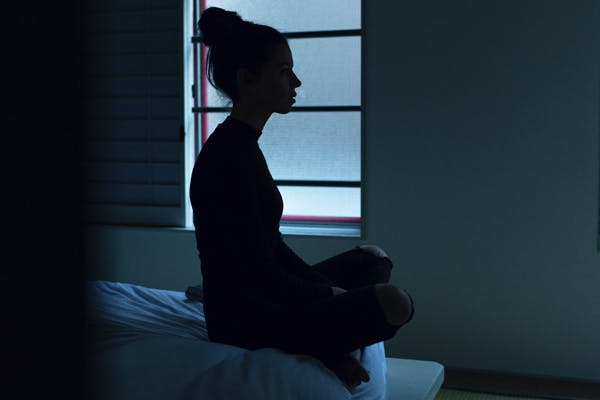 woman sitting up because she can't get comfortable in bed