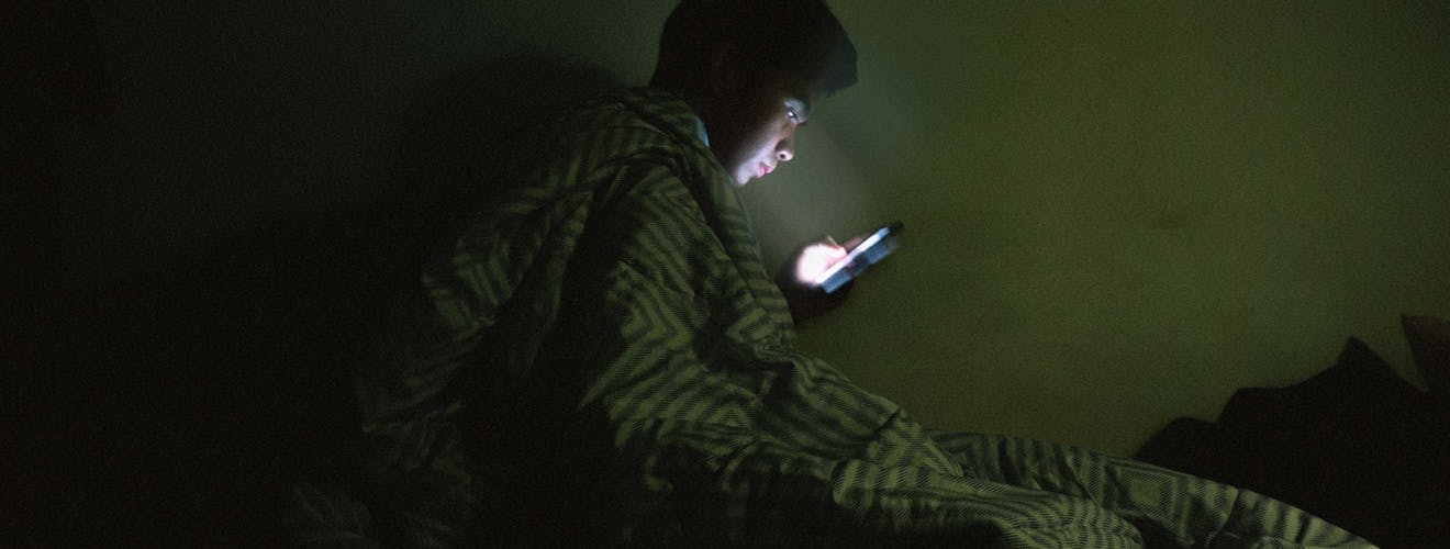man on phone in bed searching for best sleep fan