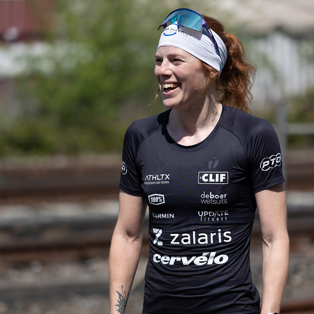 Flora College wearing cycling sunglasses and a jersey while smiling away from the camera