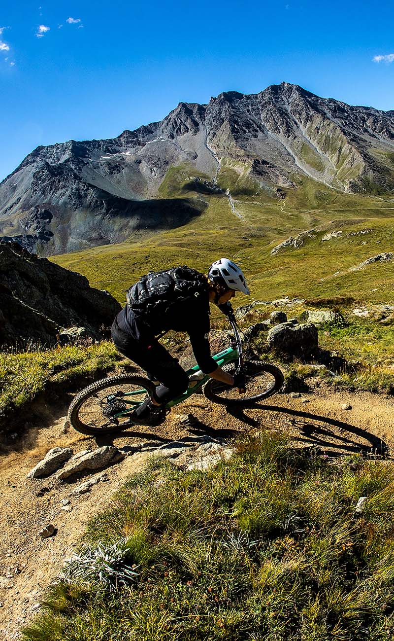 A mountain biker descending on a Santa Cruz mountain bike with mountains in the background