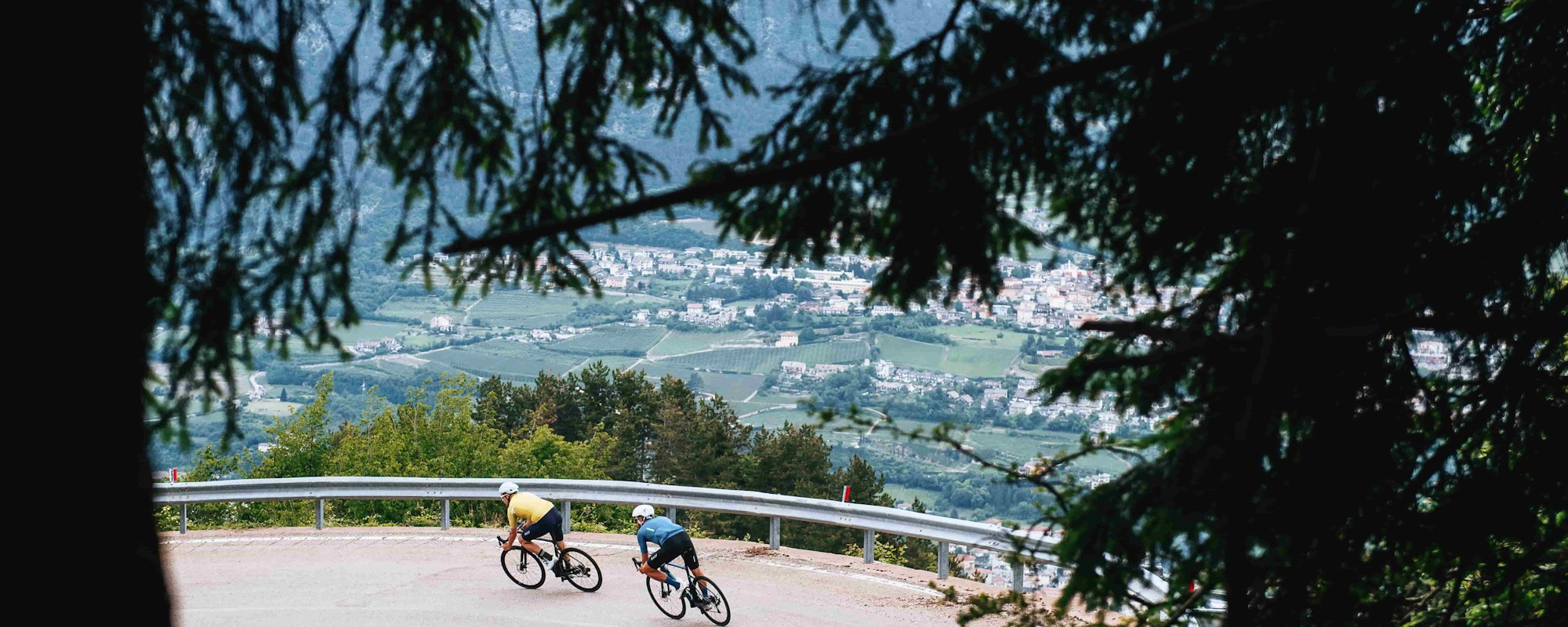 Two people descending into a city on road bikes