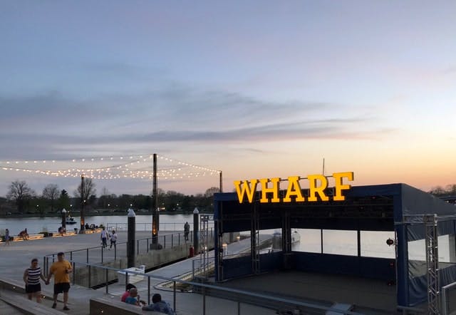 Dusk sunset overlooks a large neon sign that reads Wharf. 