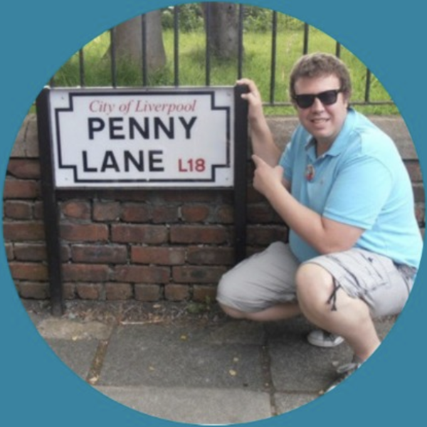 Andrew smiling next to a road sign that says, Penny Lane.
