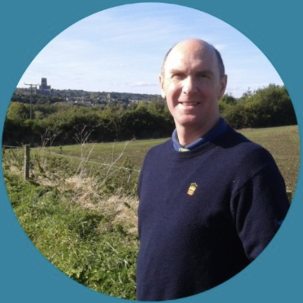 Terry Allison smiling at the camera whilst standing in a sunny field.