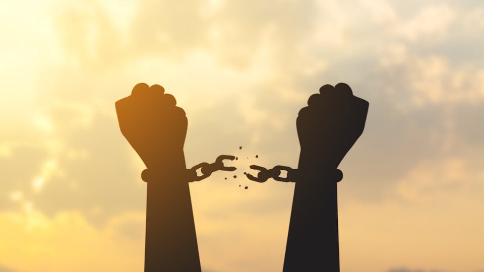 silhouette hand with chain is absent and blurred sky in sunrise background