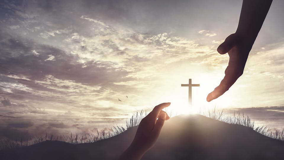 redemption concept, God's helping hand and cross on sunset background