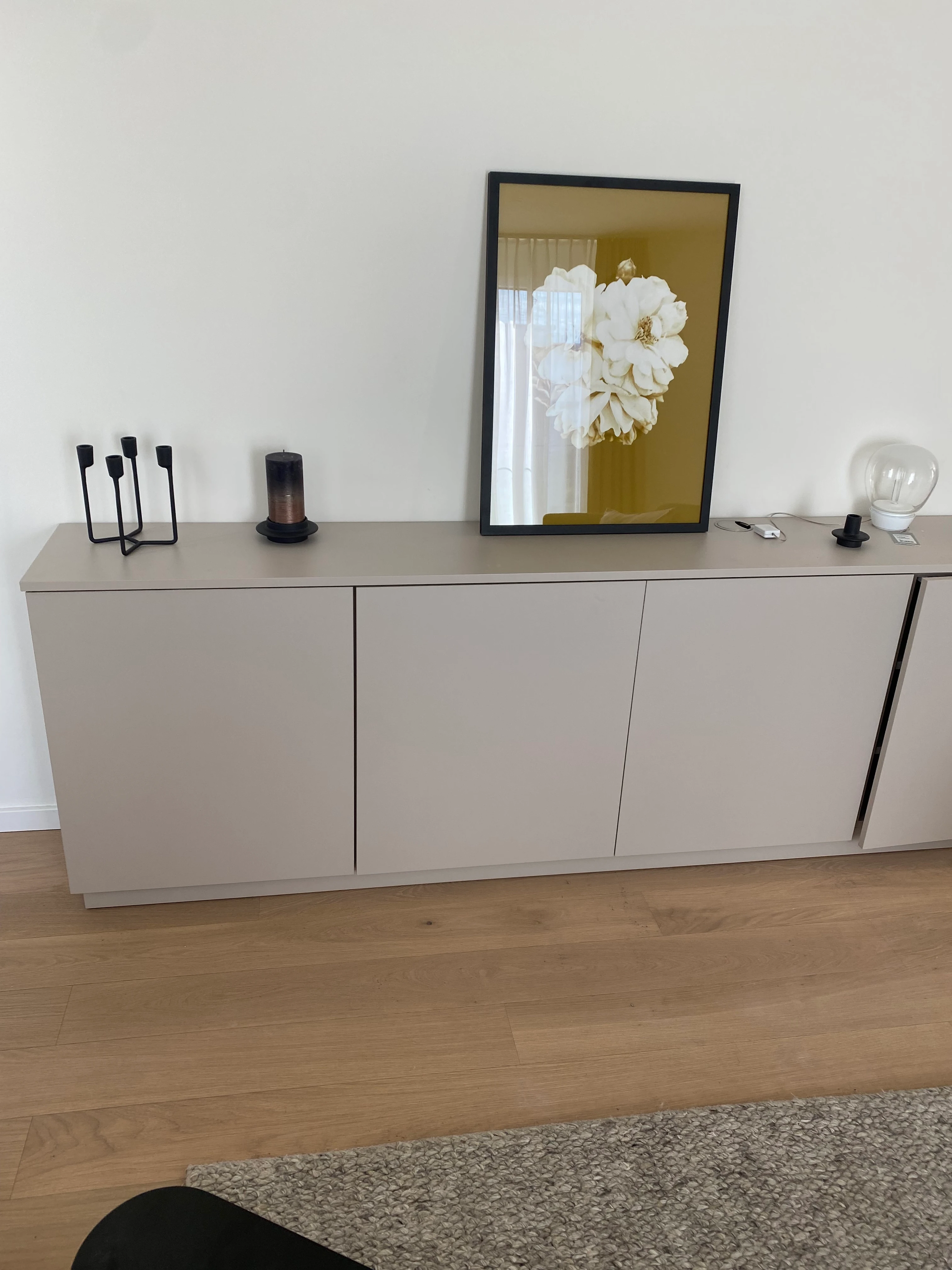 Detailaufnahme von verlegtem Bauwerk Echtholzparkett vor einem minimalistischen, beigen Sideboard in Heilbronn.