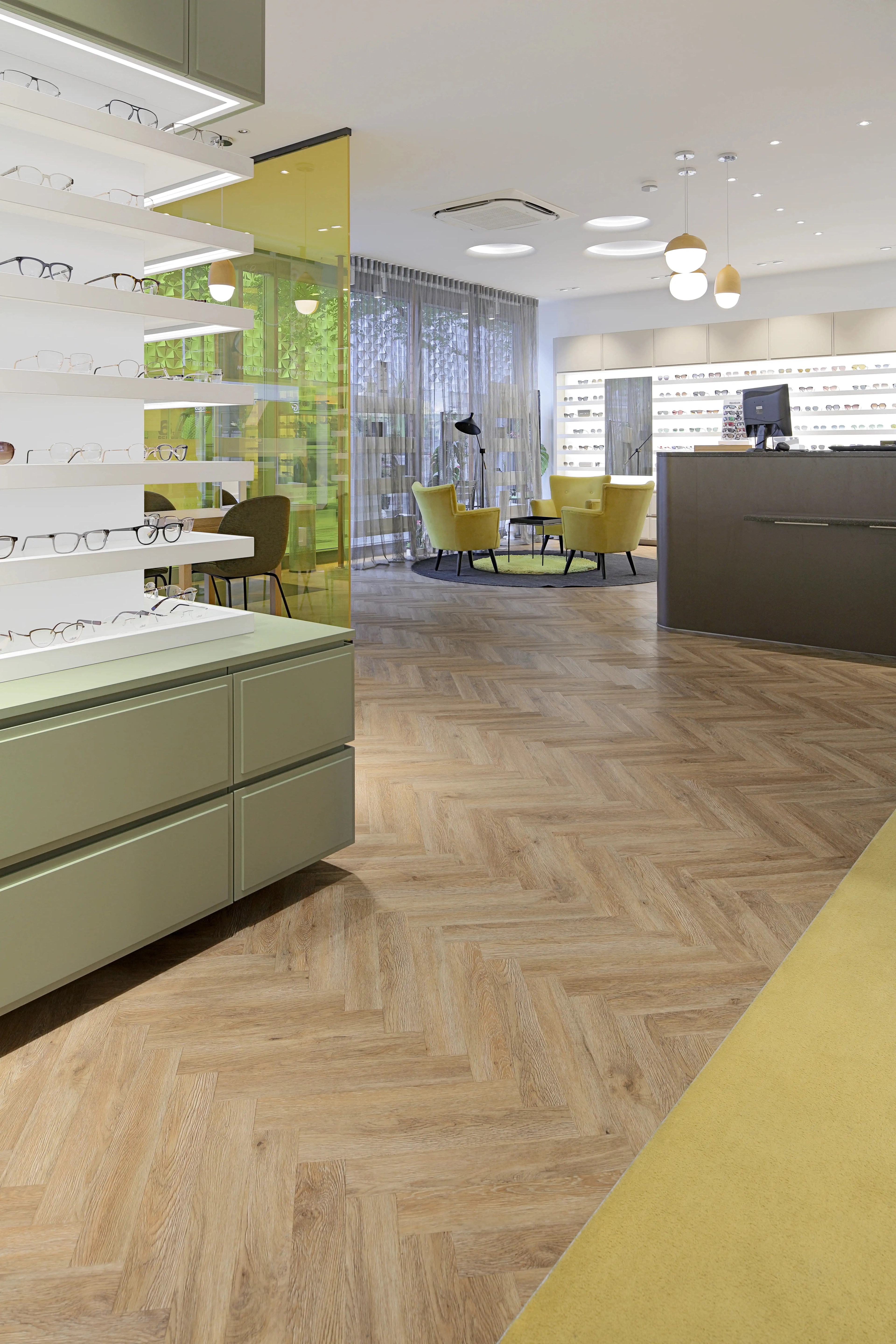 Blick in den großzügigen, modernen Verkaufsraum des Optikers in Pforzheim mit der von Parkett Saussele sanierten und mit 250 m² Fischgrät-Vinyl ausgelegten Bodenfläche.