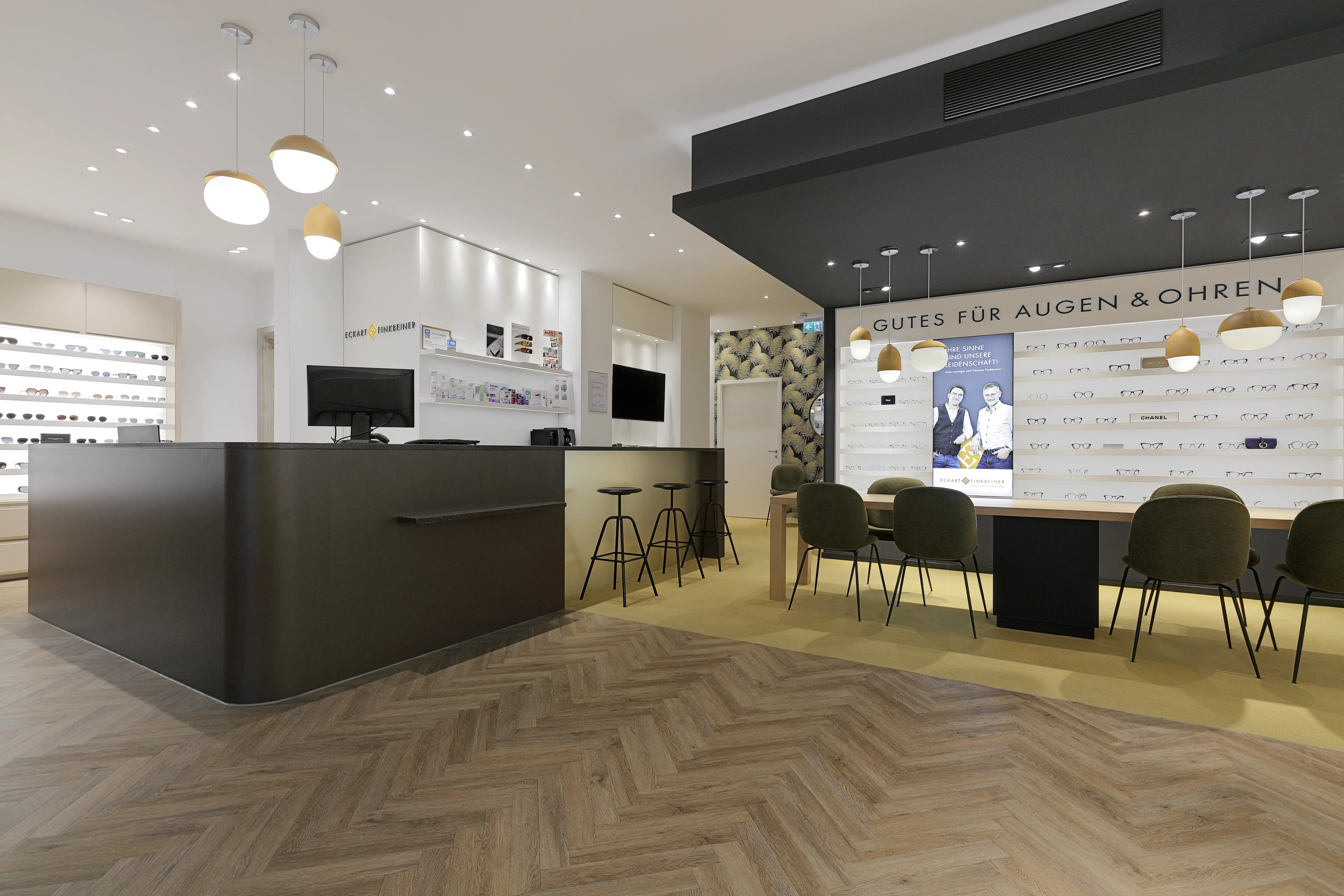 Moderner Verkaufsraum mit einer großen, dunklen Empfangstheke und stilvollem Fischgrät-Vinylboden im Eichen-Look, professionell verlegt auf der 250 m² großen Ladenfläche in Pforzheim.