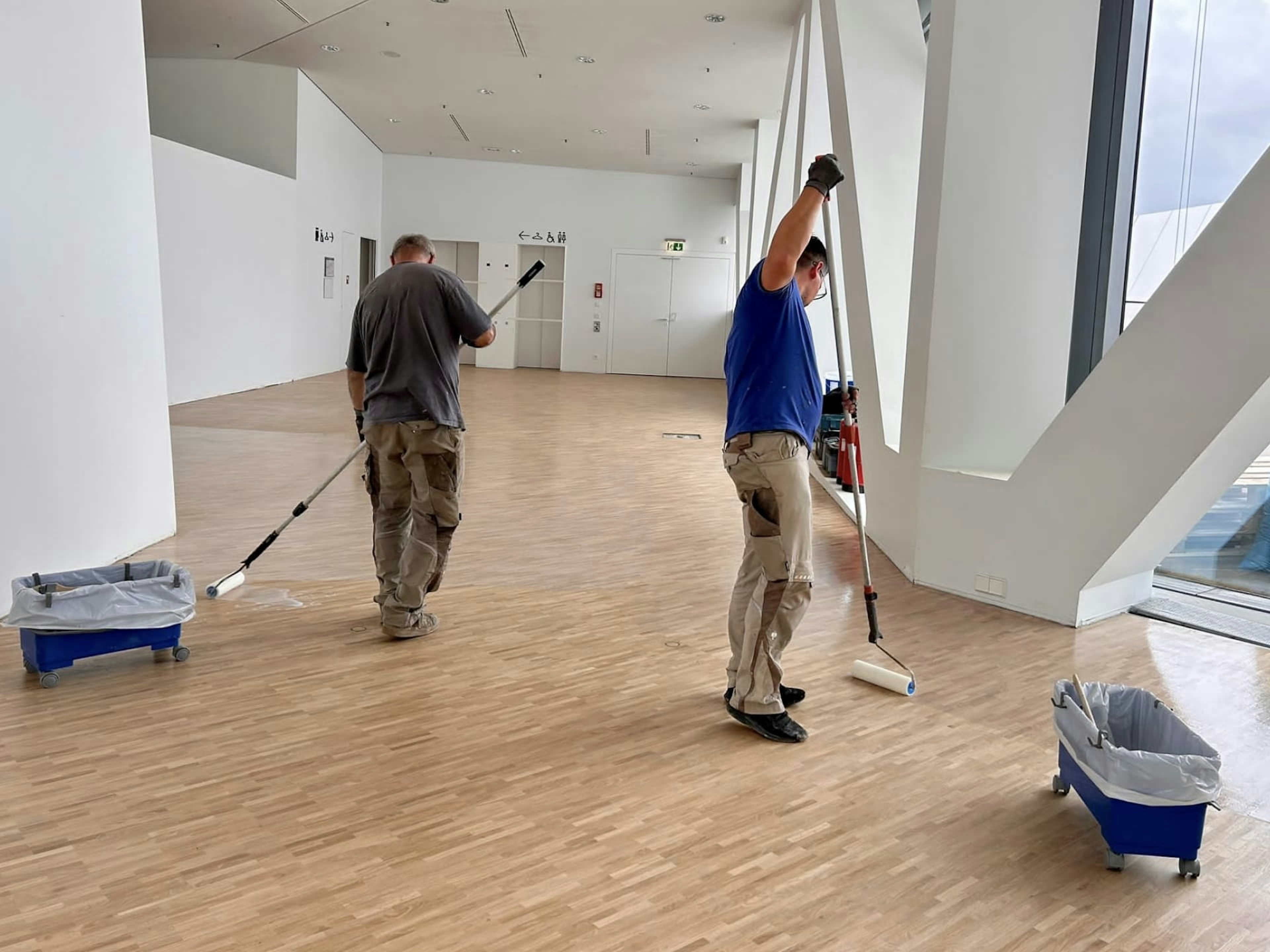 Mitarbeitende von Parkett Saussele bei der Pflege und Reinigung des Parkettbodens im Porsche Museum Stuttgart