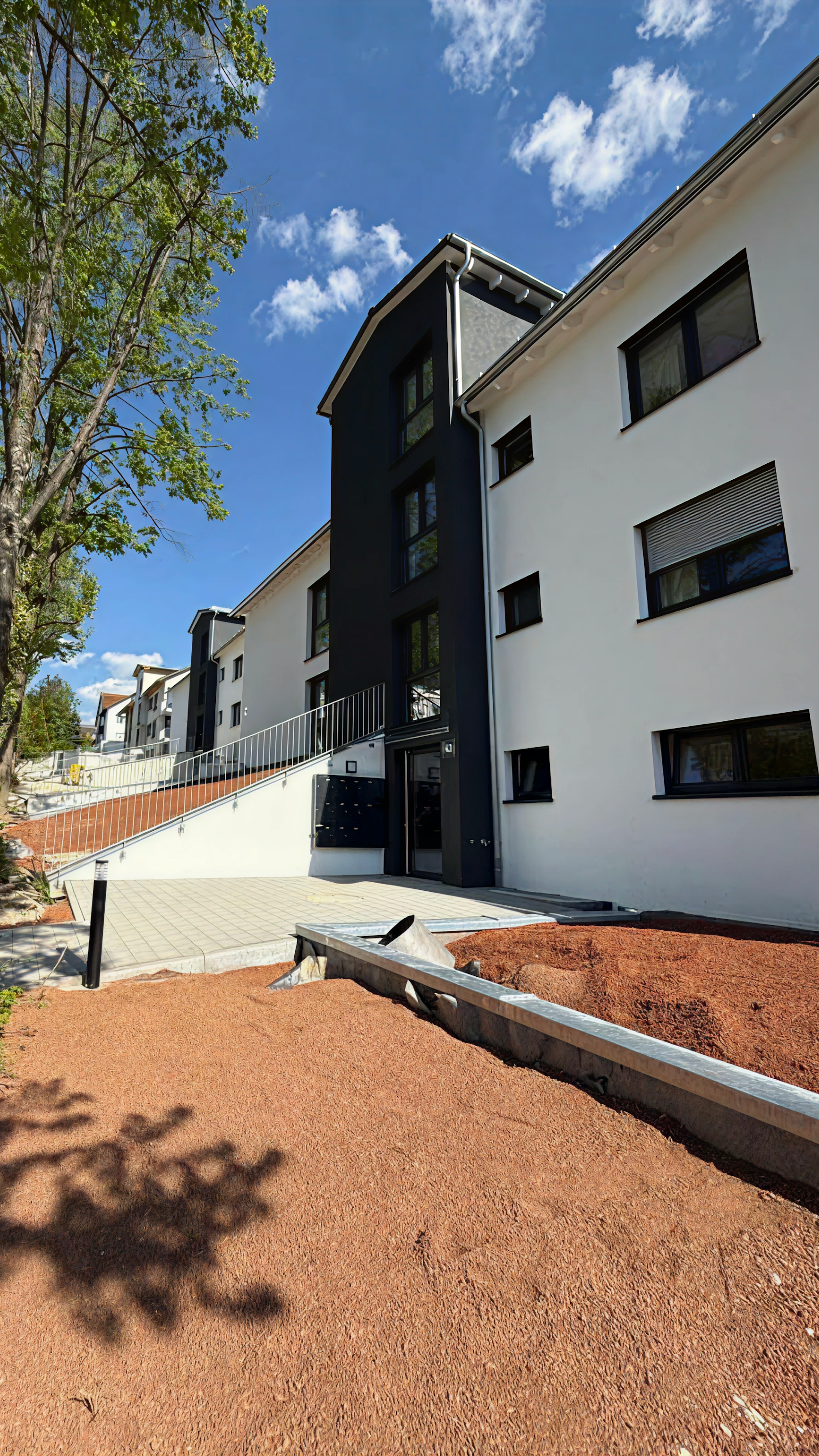 Barrierefreier Hauseingang mit moderner Rampe und dunklem Fassadenelement