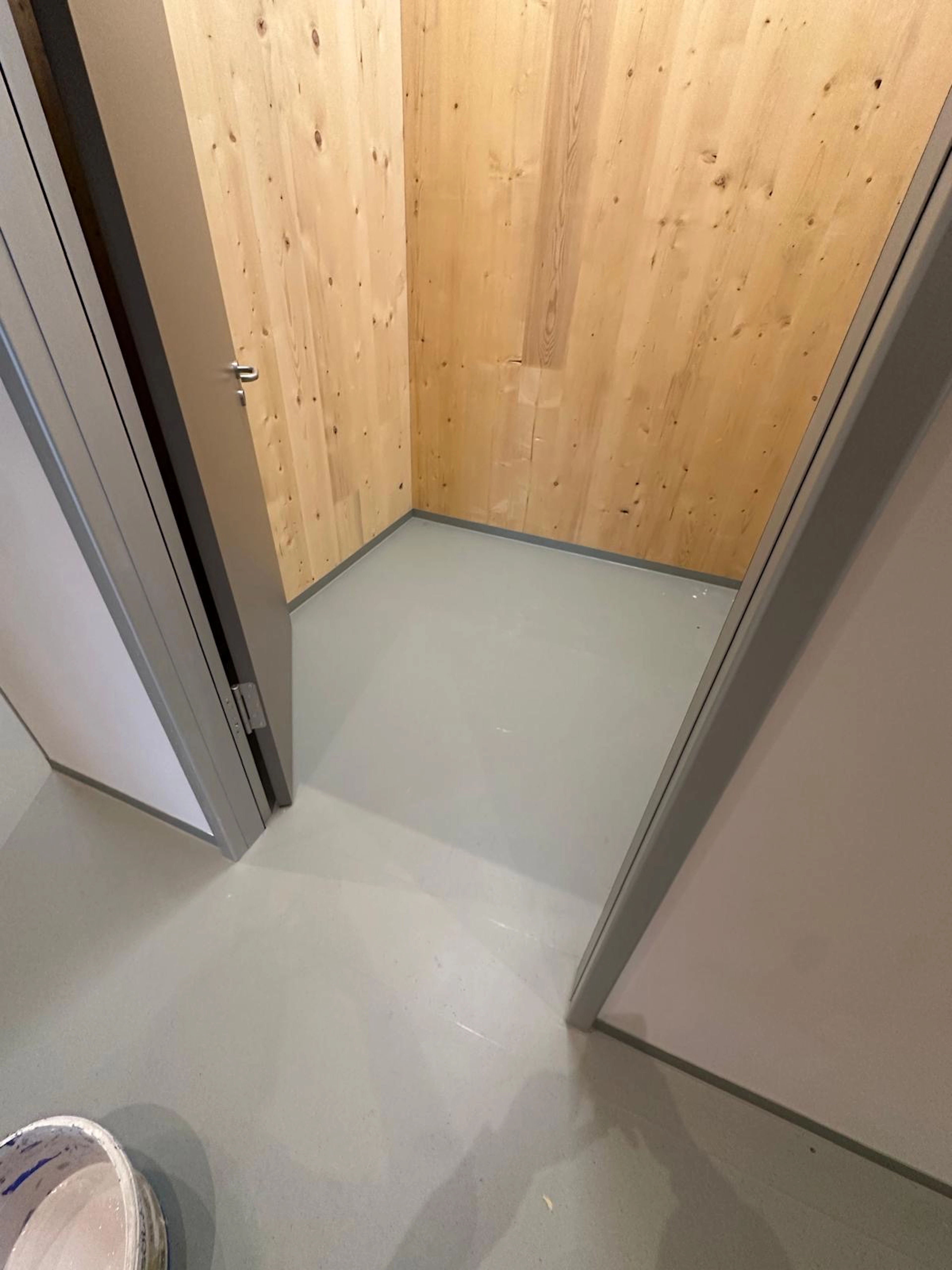 Kombination aus grauem Boden und heller Echtholzwand in einem Nebenraum