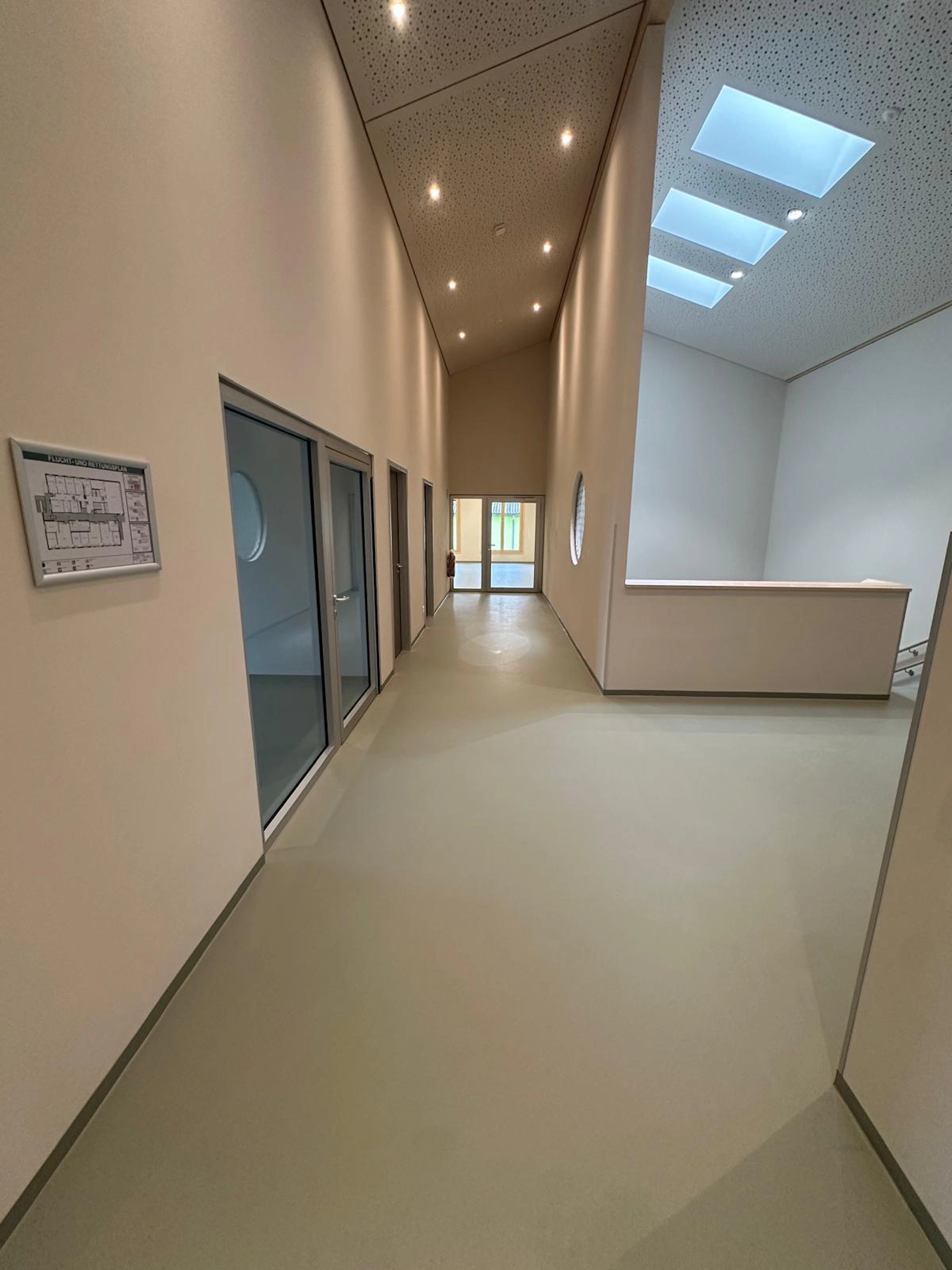 Lichtdurchfluteter Flur mit fugenlosem grauem Boden und moderner Architektur