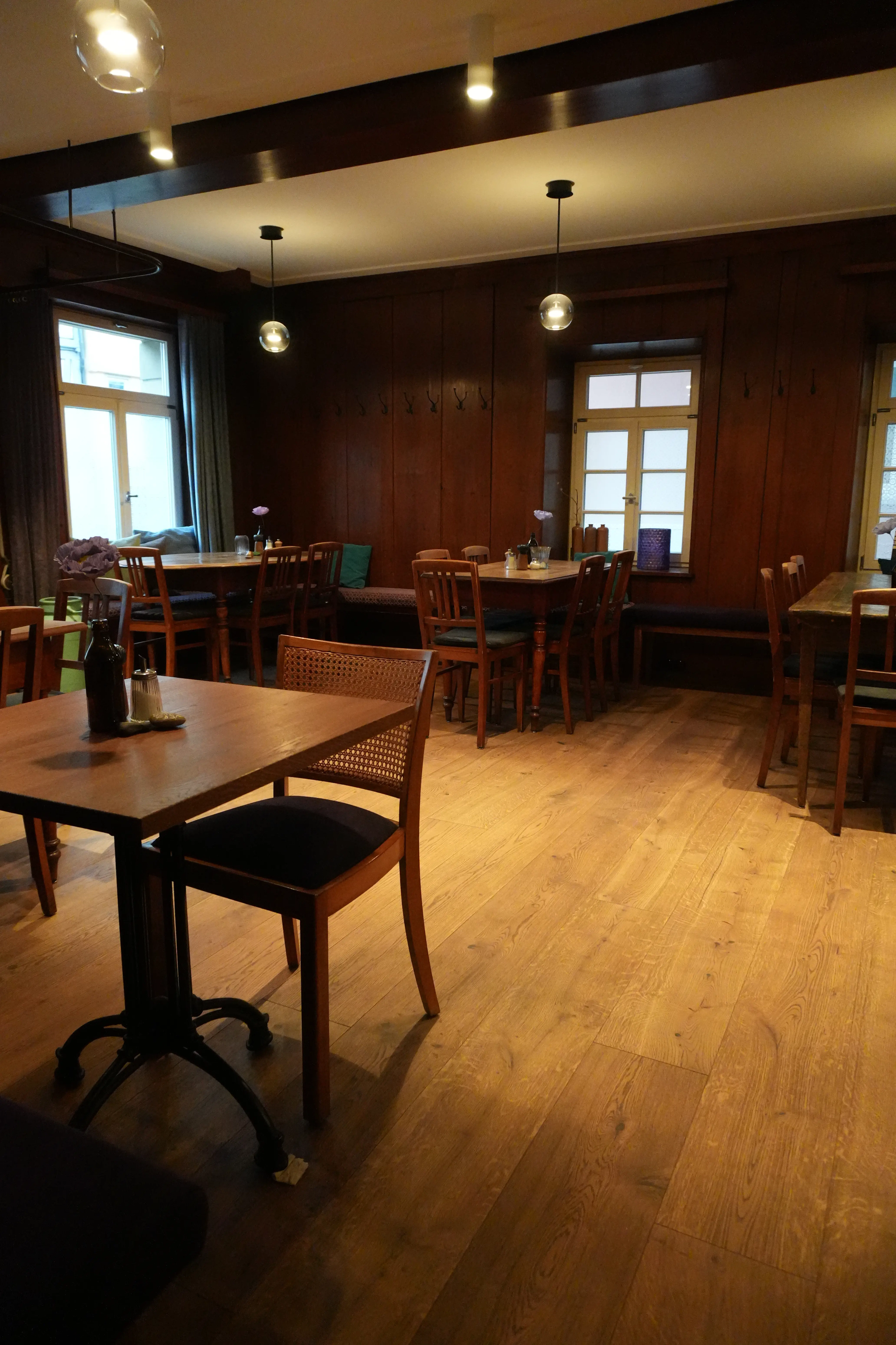 Rustikale Gaststube mit dunkler Wandvertäfelung und Echtholzparkett am Boden