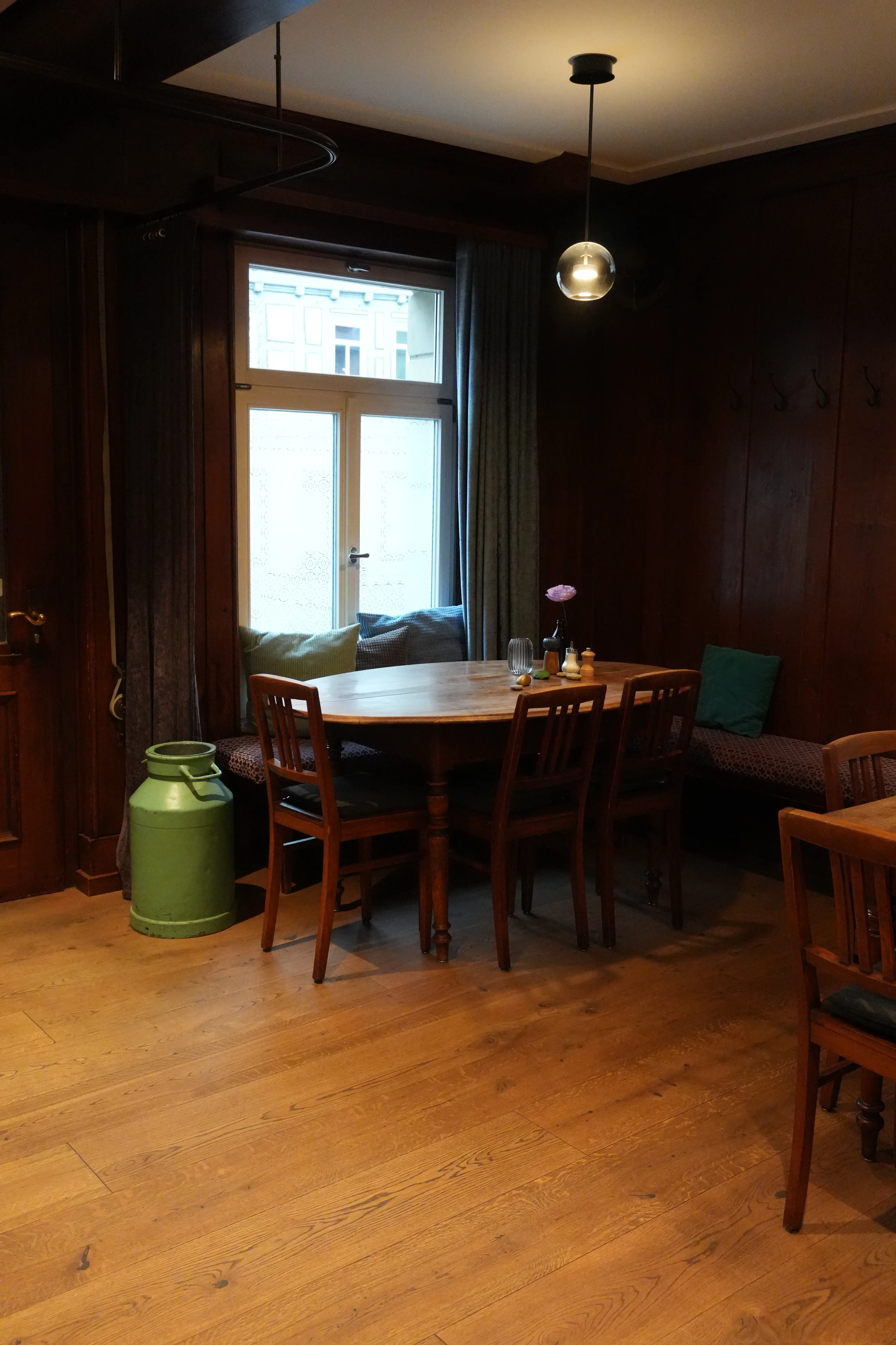 Gemütliche Sitzecke am Fenster mit hellem Dielenboden und grüner Milchkanne