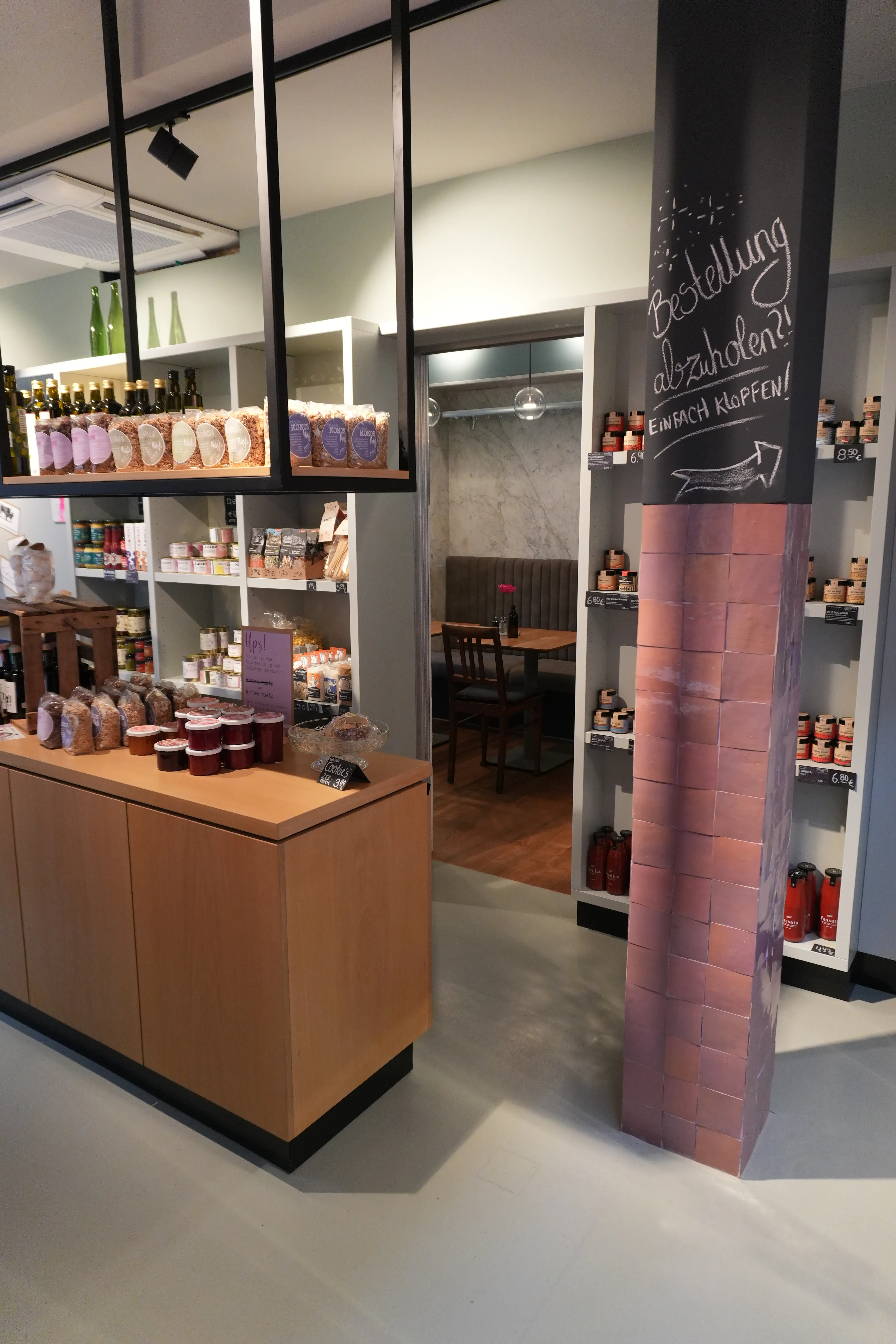 Fugenloser grauer Bodenbelag im Shop und Parkettboden im angrenzenden Gastraum