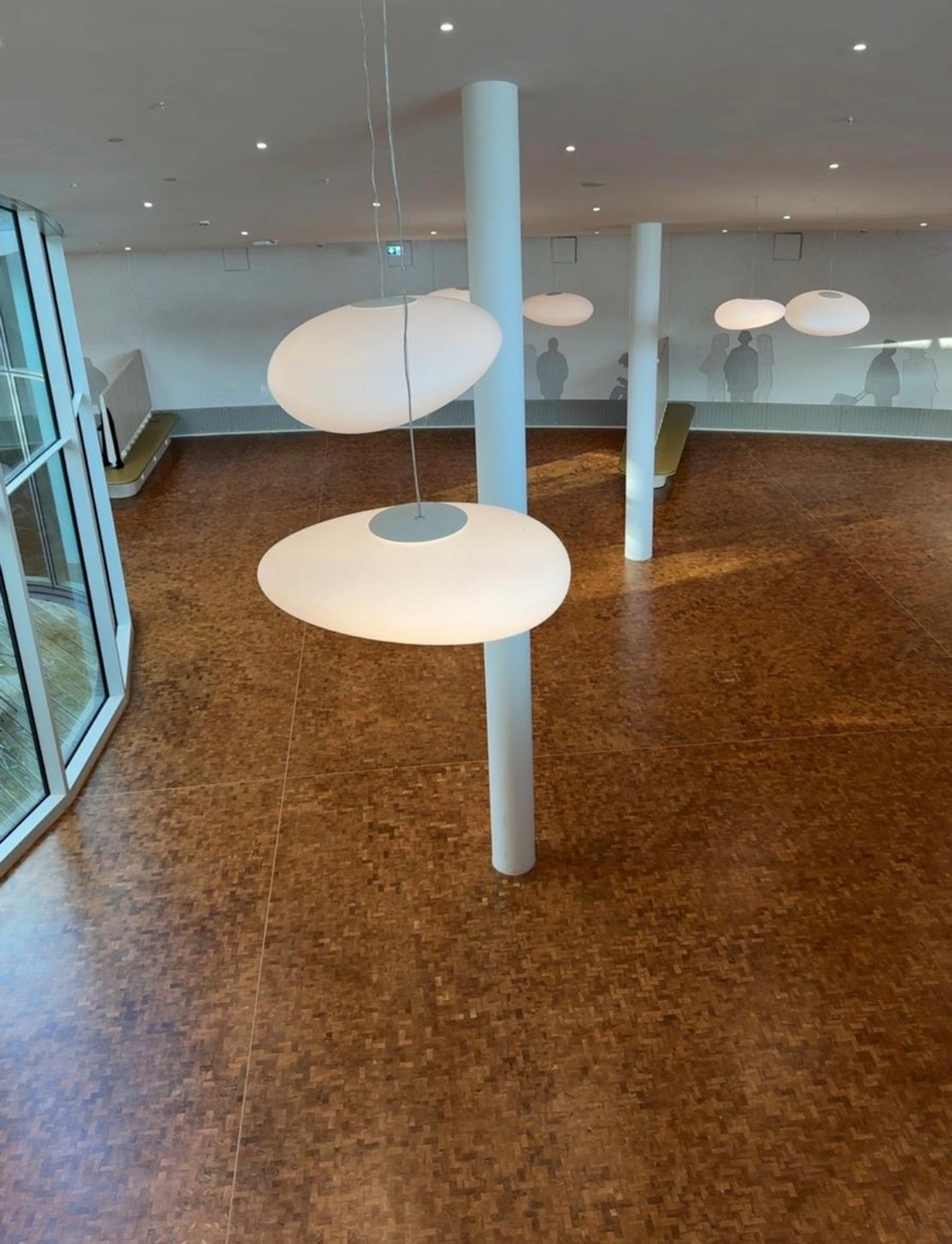 Großflächiges Mosaikparkett in einer modernen Mensa mit weißen Säulen und Designlampen