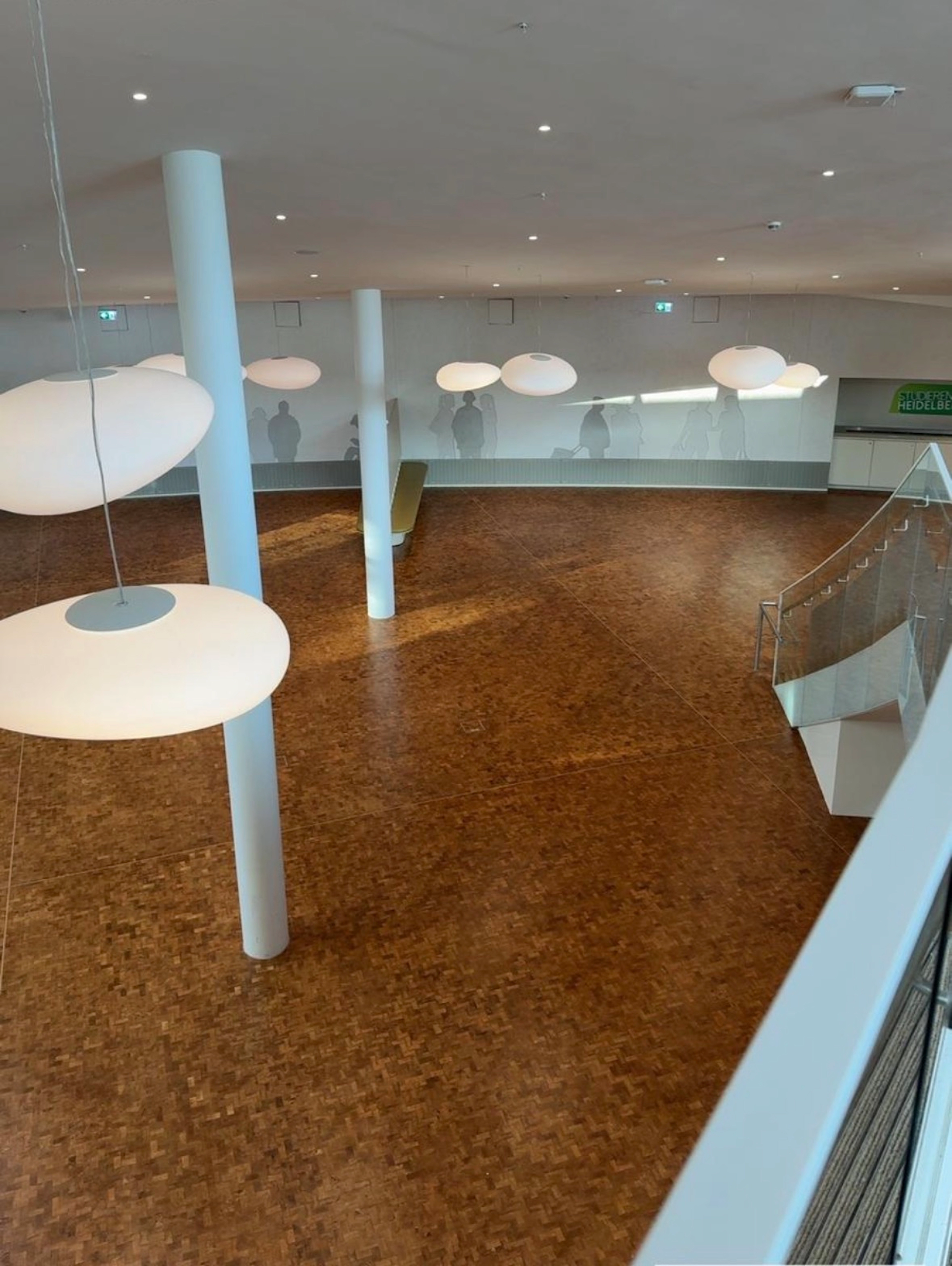 Lichtdurchflutetes Foyer mit frisch aufbereitetem Industrieparkett und Glasgeländern