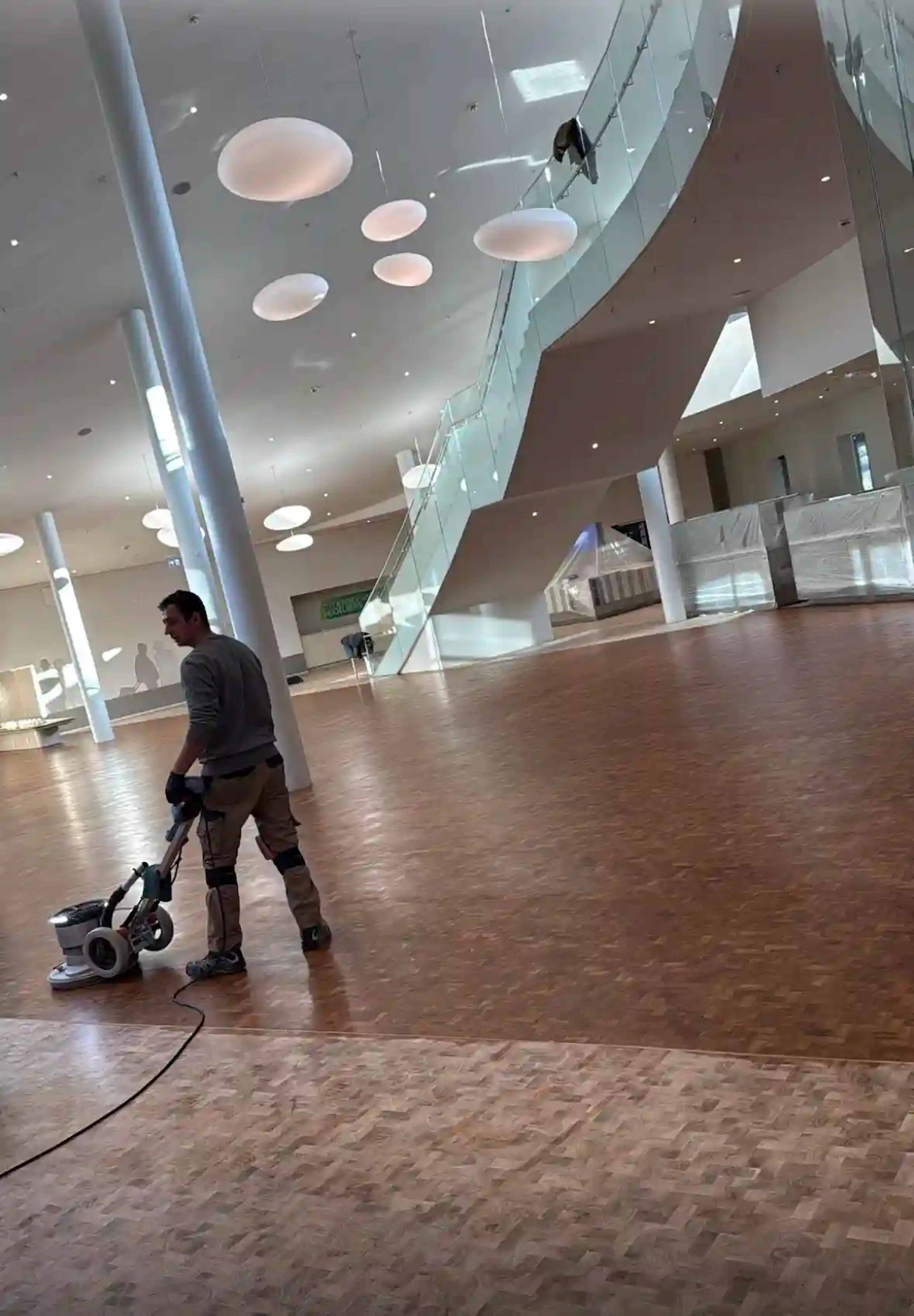 Handwerker bei der professionellen Parkettreinigung mit einer Einscheibenmaschine