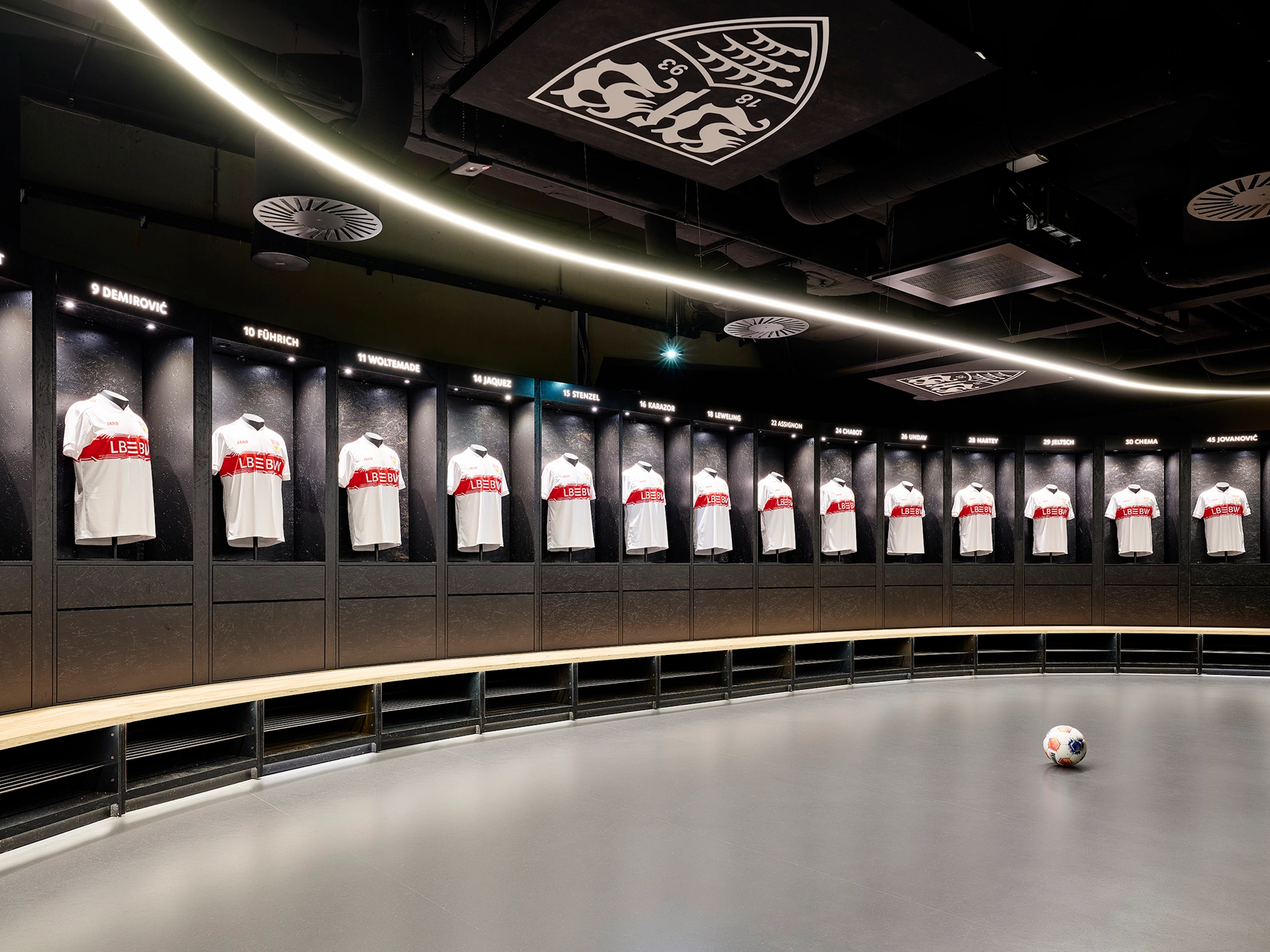 Fachmännisch verlegter, dunkelgrauer Boden in der Umkleidekabine der MHP Arena, gesäumt von schwarzen Spinden mit VfB-Trikots und einem Fußball auf dem Boden.