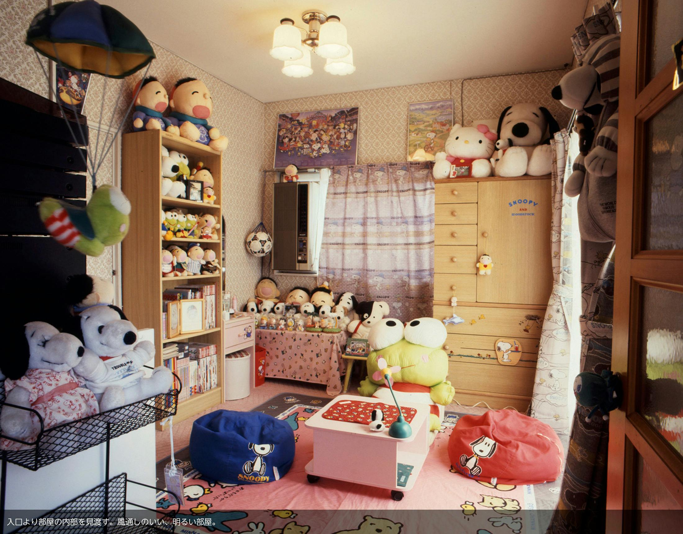 A photograph taken by Kyoichi Tsuzuki from TOKYO STYLE showing a young woman's stuffed animal filled studio apartment