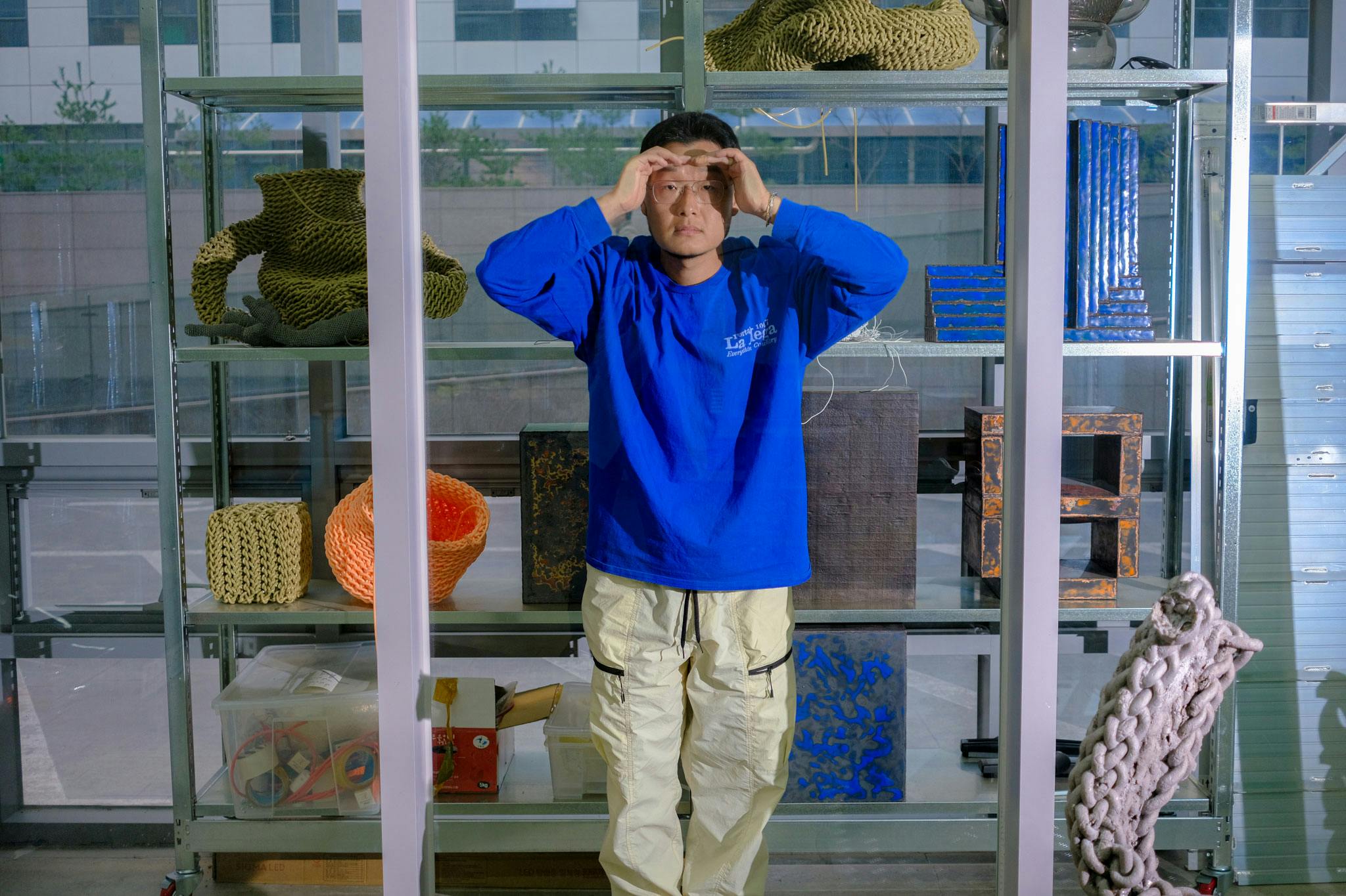 Kwangho Lee in his Seoul Studio with an archive of pieces in enamel and woven PVC behind him