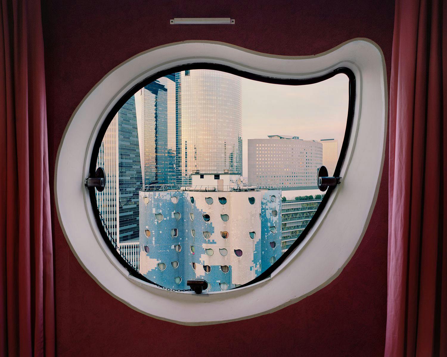 The windows of the Aillaud Towers in Nanterre are notable for their distinctive irregular shapes and placements. The windows vary in size and are arranged in an unconventional, scattered pattern across the façades. 