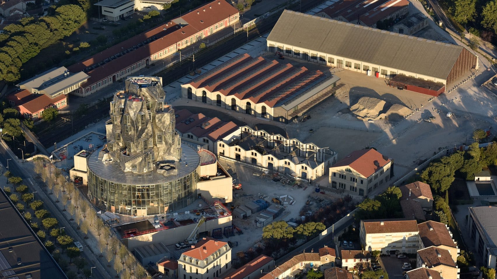  Luma Arles is a cultural complex that includes seven buildings. The most prominent among these is the 56-meter-high tower designed by Frank Gehry, which serves as the centerpiece. The other six buildings are renovated industrial structures from the 19th century, repurposed to host various exhibitions, workshops, and artistic activities