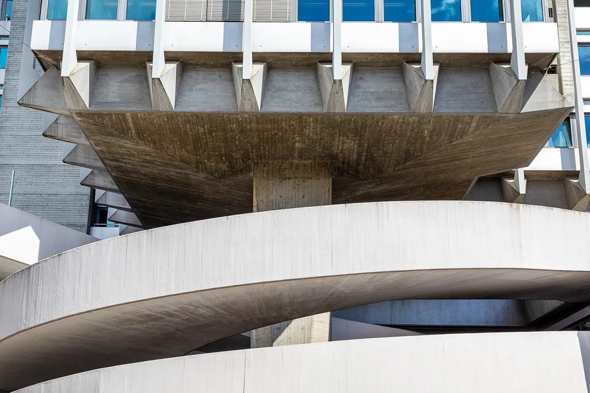 The building has a strong vertical orientation, with 20 floors, giving it a slender and elegant appearance. This verticality is accentuated by the continuous lines of windows running up the facade, reinforcing the tower-like form.