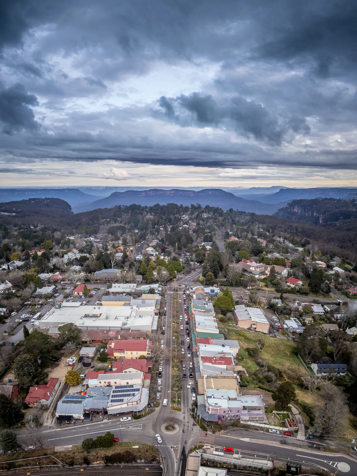The town of Katoomba from above. A road is pointing towards the mountain range and valley