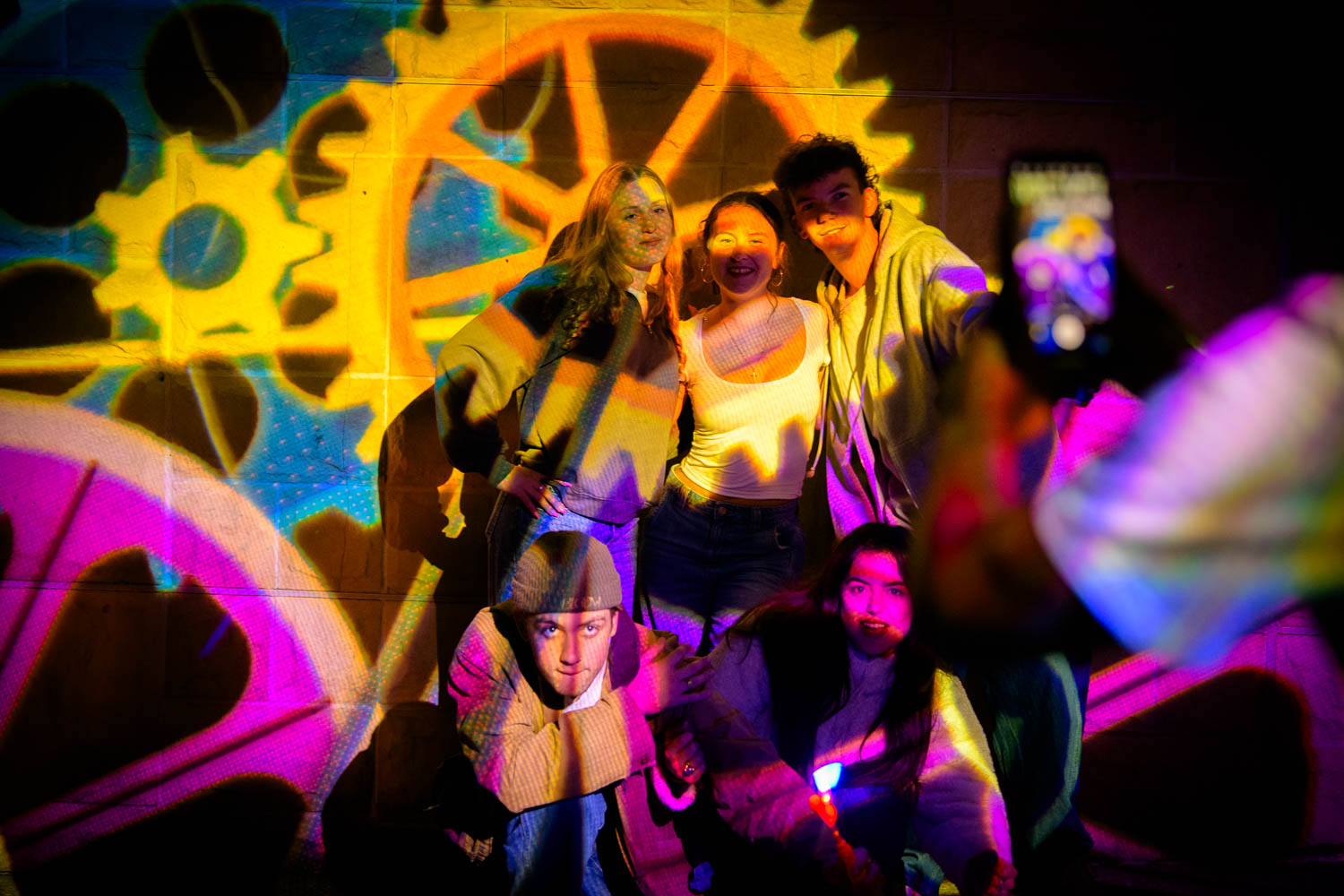Group of young adults in front of light projection on faces