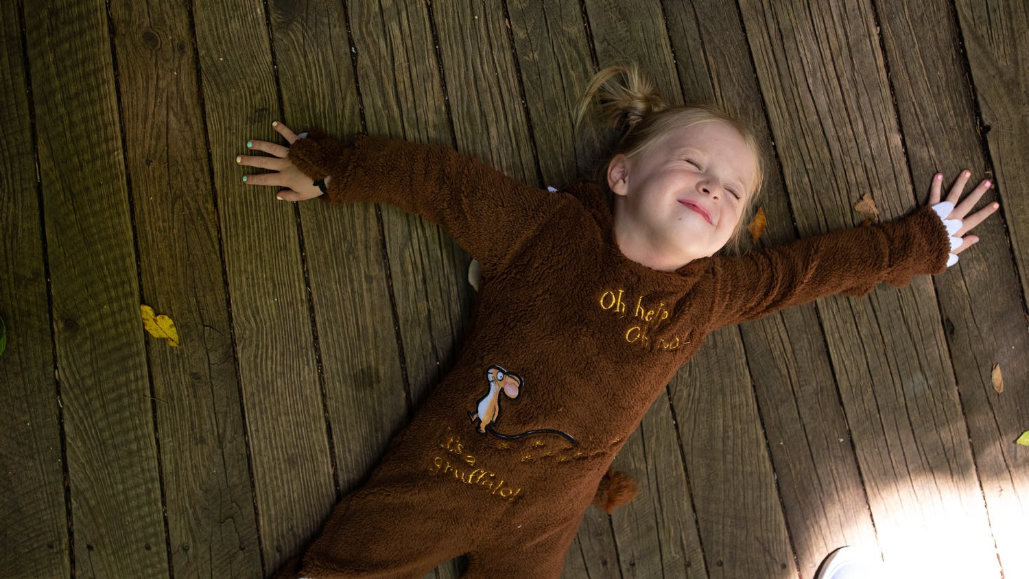 Girl in Gruffalo outfit lying down on Scenic Walkway boardwalk smiling