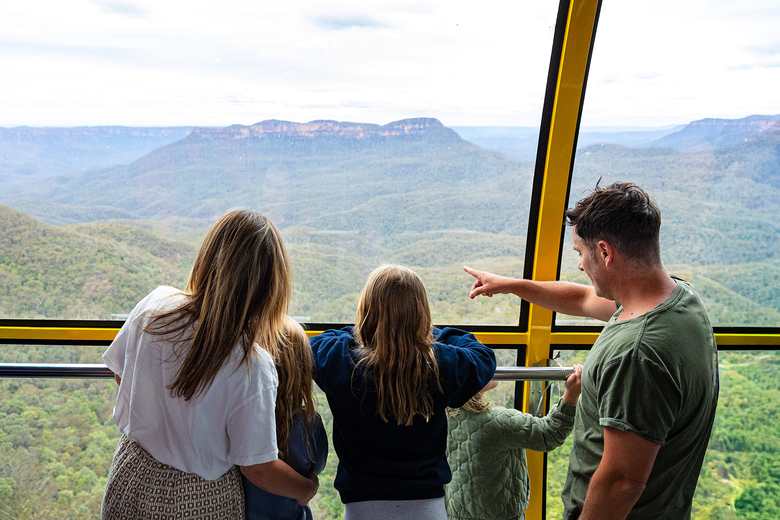 A family inside the Scenic Skyway cablecar point out to the valley and Mount Solitary