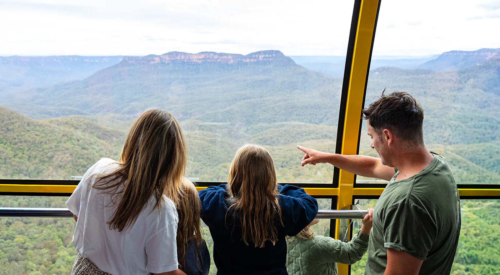 A family inside the Scenic Skyway cablecar point out to the valley and Mount Solitary