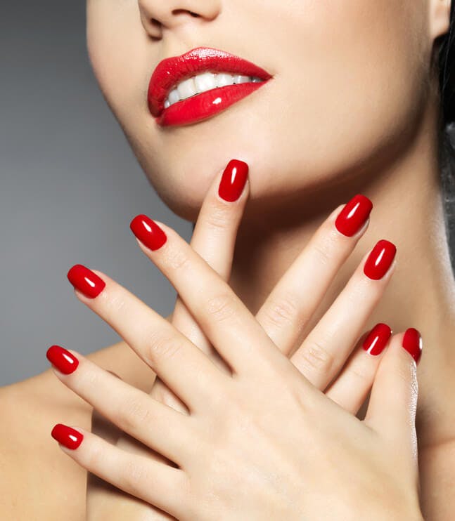 Two hands of a woman with perfectly red painted nails.