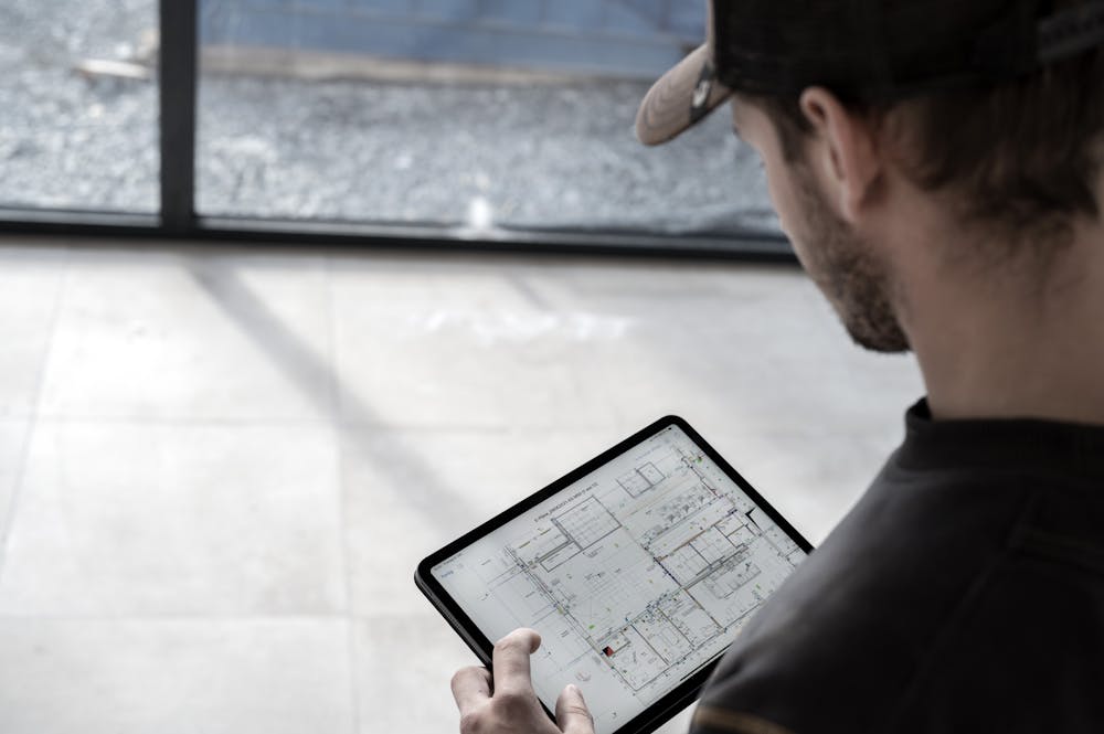 Mitarbeiter mit digitalem Plan auf einer Baustelle