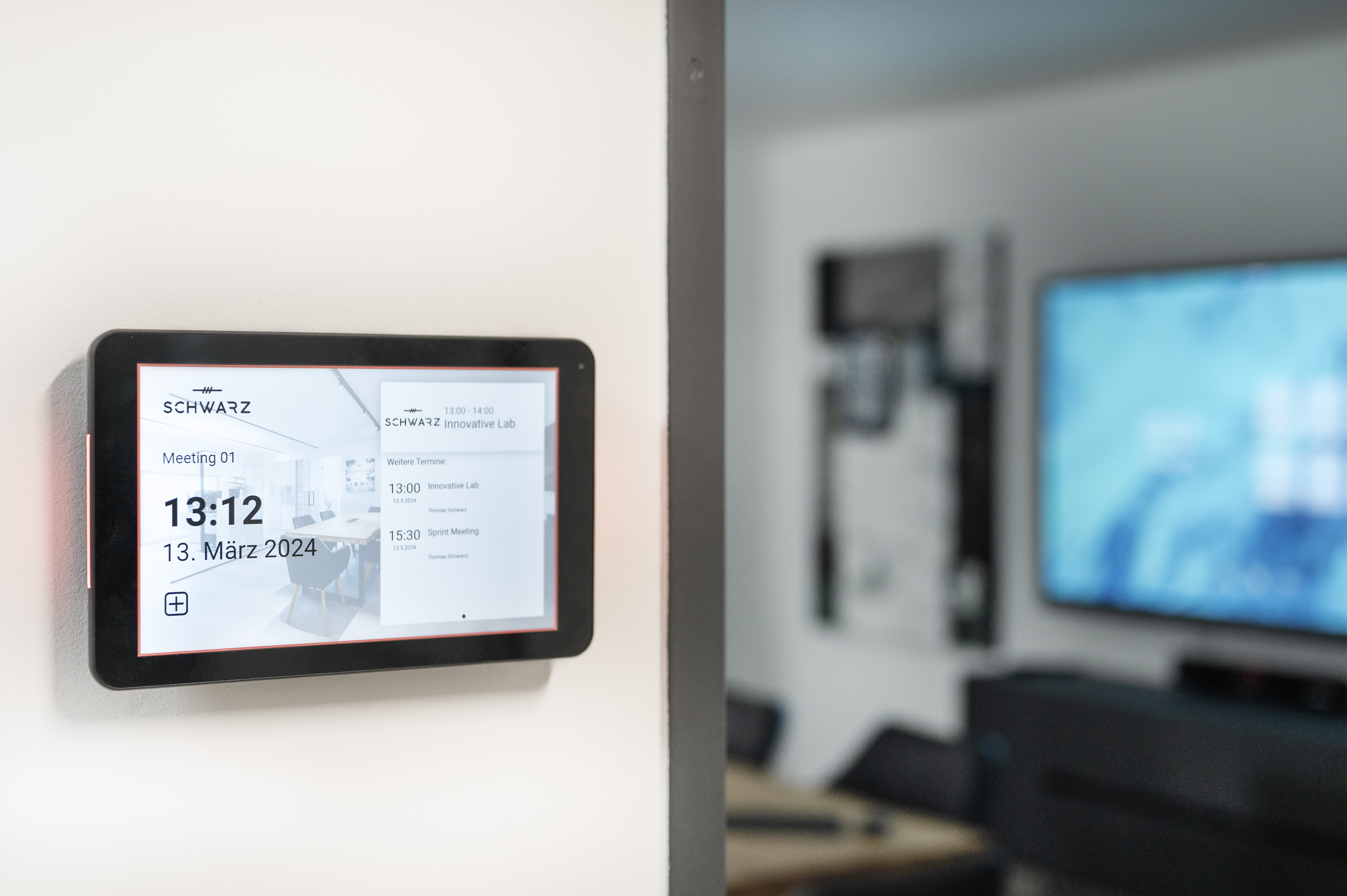 Room Manager mit Besprechungsraum und Display im Hintergrund