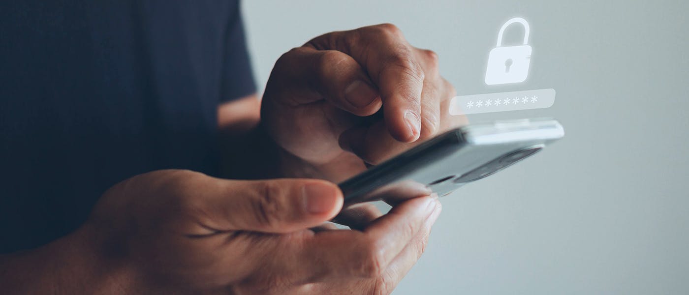 Hands holding a mobile phone and typing in a password