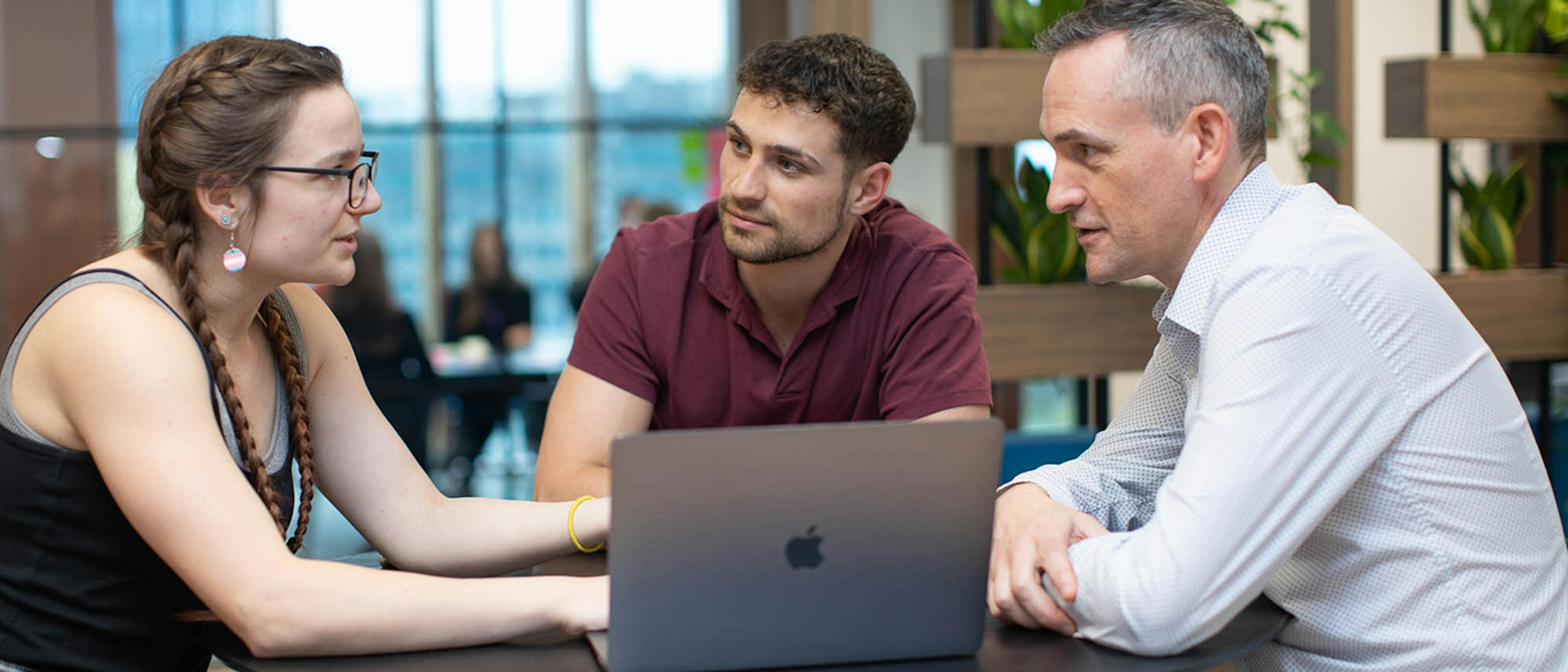 Three people in a discussion around a computer