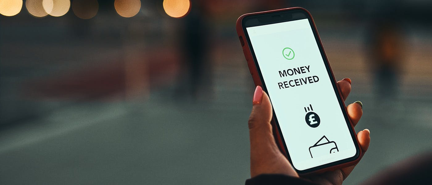 Hand holding a mobile phone with Payment Received written on the screen