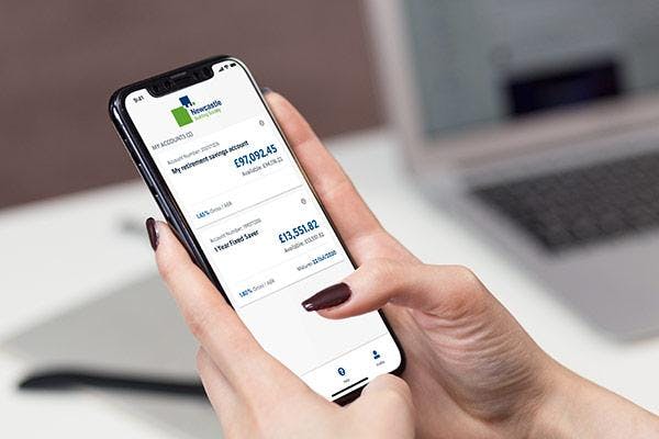 Hands holding a mobile phone displaying a banking app