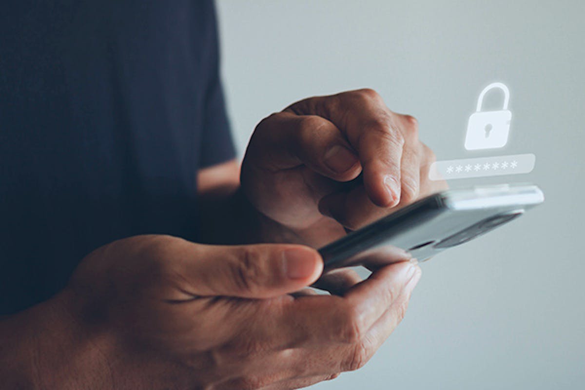 Hands holding a mobile phone and typing in a password