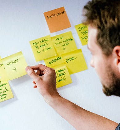 Man adding sticky notes to a wall