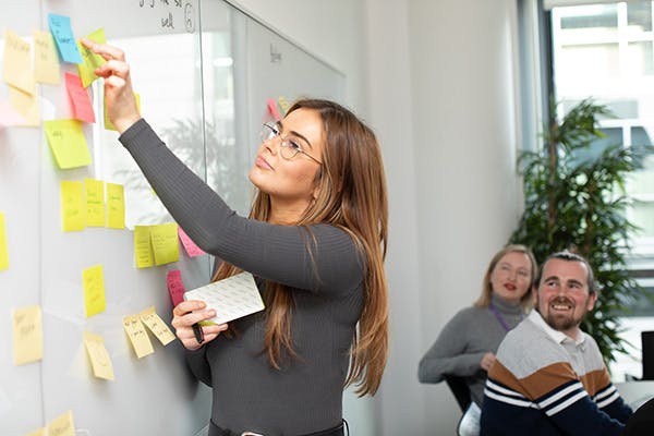 Woman adding sticky notes to a whiteboard in a meeting