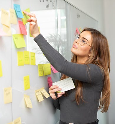 Woman adding sticky notes to a whiteboard in a meeting