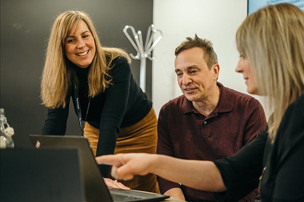 Woman at a laptop presenting to two colleagues